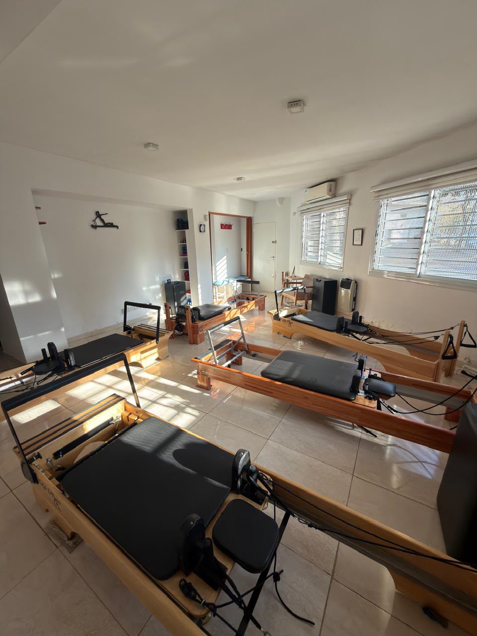 Sala de Benincasa Pilates con camillas reformer de madera junto a ventanas con luz natural